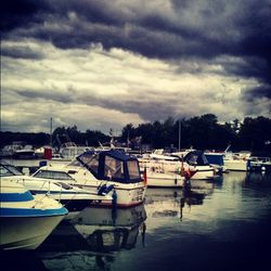 Boats in sea against cloudy sky