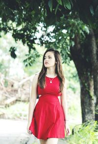 Teenage girl standing against trees