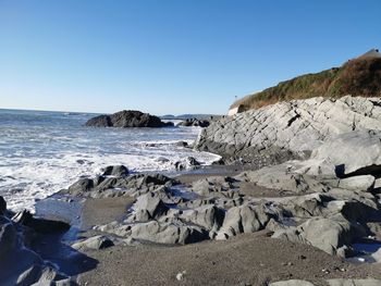 Rocks on beach against clear blue sky