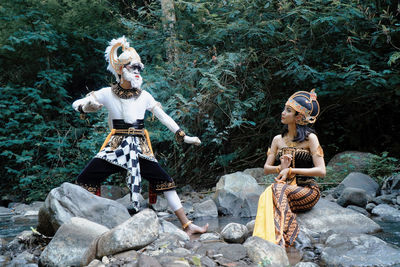 Full length of woman sitting on rock