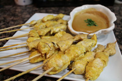 Close-up of chicken skewers served with peanut sauce in plate