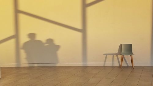 Shadow of man on chair against wall