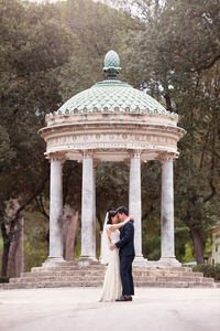 Side view of wedding couple standing by gazebo in park