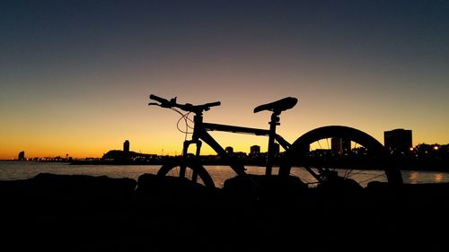 Silhouette of bicycle on beach against clear sky