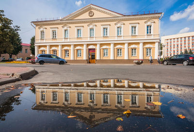 Building by street in city against sky