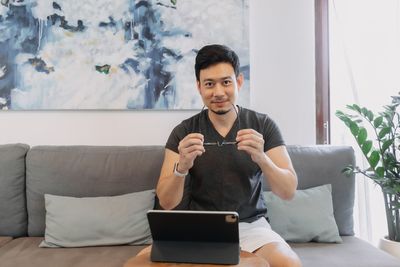 Young woman using phone while sitting on sofa at home