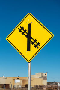 Low angle view of road sign against clear blue sky