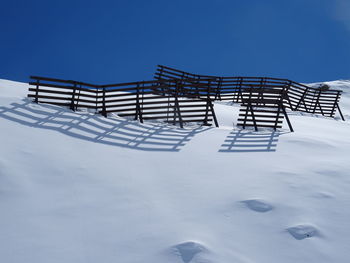 Built structure on snow covered field against clear blue sky