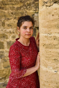 Portrait of teenage girl standing against wall