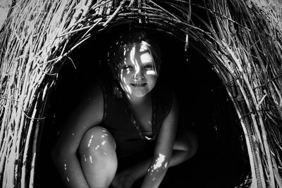 Portrait of smiling girl crouching in hut