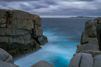 Scenic view of rocks by sea against sky