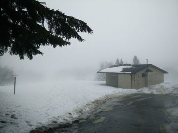 House on snow covered landscape in foggy weather