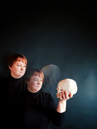 Full length portrait of woman  standing against black background