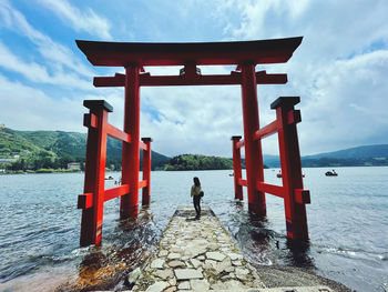 Rear view of man standing by sea against sky