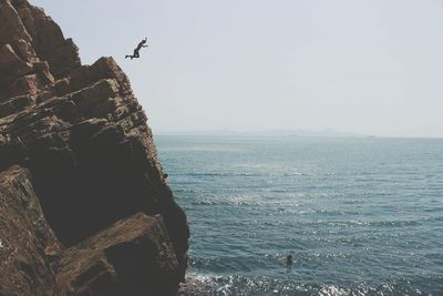 Silhouette person jumping into blue sea