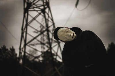 Low angle view of silhouette person holding camera against sky