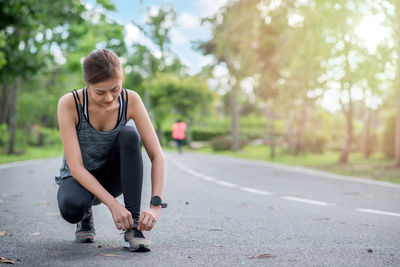 Young woman looking away while walking on road