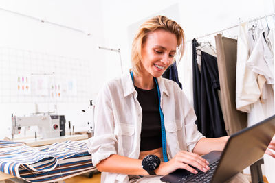 Smiling female designer using laptop at studio