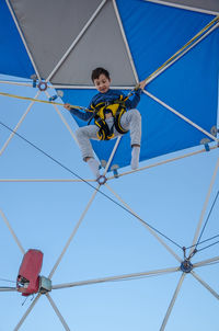 Low angle view of man working on rope against sky