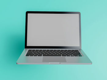 Close-up of laptop on table against blue background