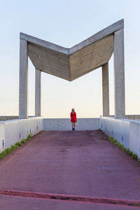 Rear view of woman standing on footpath against sky