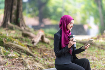 Full length of young woman using mobile phone outdoors