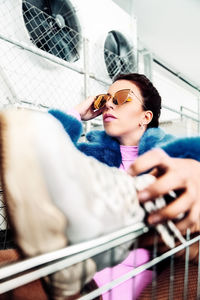 Young woman wearing sunglasses while sitting in shopping cart