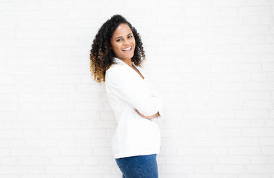 Portrait of woman standing against white wall