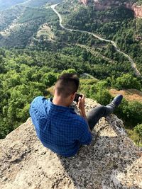 High angle view of man sitting on mountain in forest