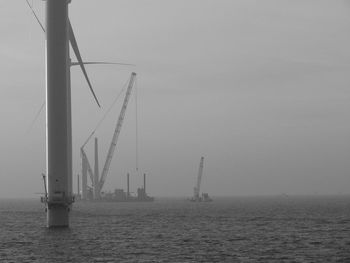 Wind turbines in sea against sky