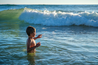 Boy having fun jumping in ocean sea waves