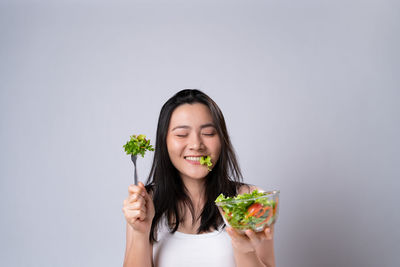 Portrait of woman holding ice cream against white background