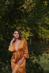 Young woman standing against trees