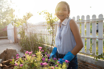 Portrait of smiling woman standing by flowering plants