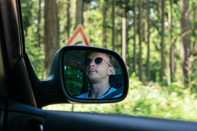 Portrait of reflection of man on side-view mirror
