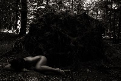 Woman lying down on tree in forest