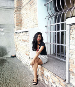 Portrait of young woman sitting on window sill