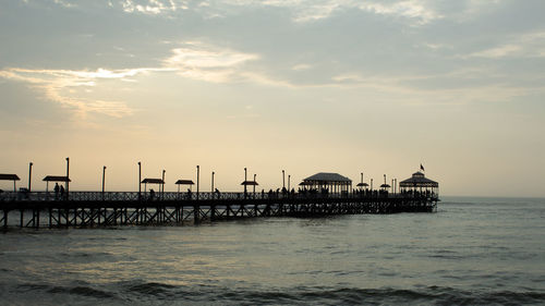 Pier over sea against sky during sunset
