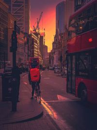 Rear view of man cycling on city street at night