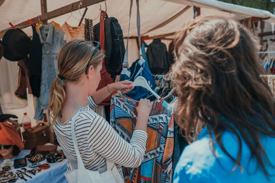 Woman with friend buying clothes at market