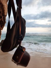 Man holding umbrella on beach against sky