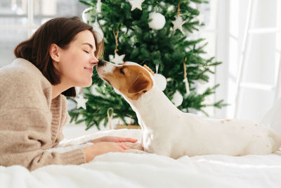 Young woman with dog sitting on bed