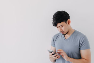 Young man using mobile phone against white background