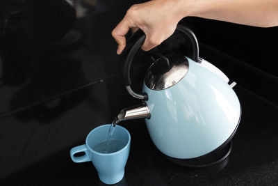 Cropped hand of person pouring coffee on table