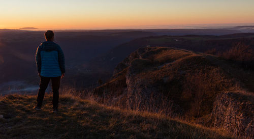 Man above the cliff of moutier-haute-pierre facing the setting sun