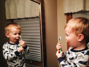 Boy holding toothbrush in front of mirror