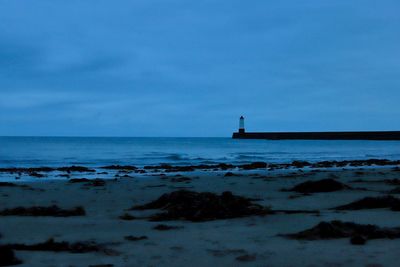 Lighthouse amidst sea and buildings against sky