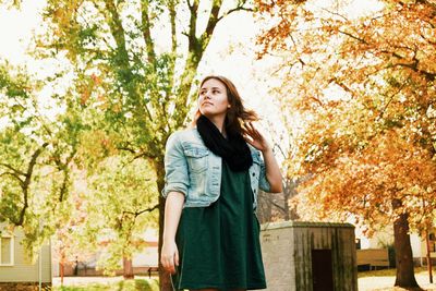 Portrait of young woman standing against trees