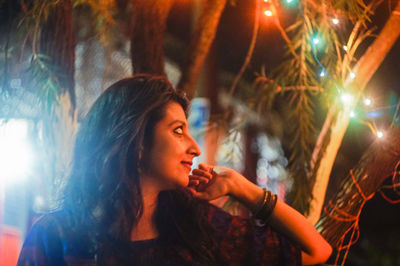 Young woman looking at illuminated fairy light decoration at night