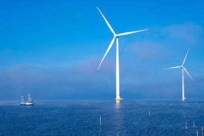 Wind turbines in water against blue sky